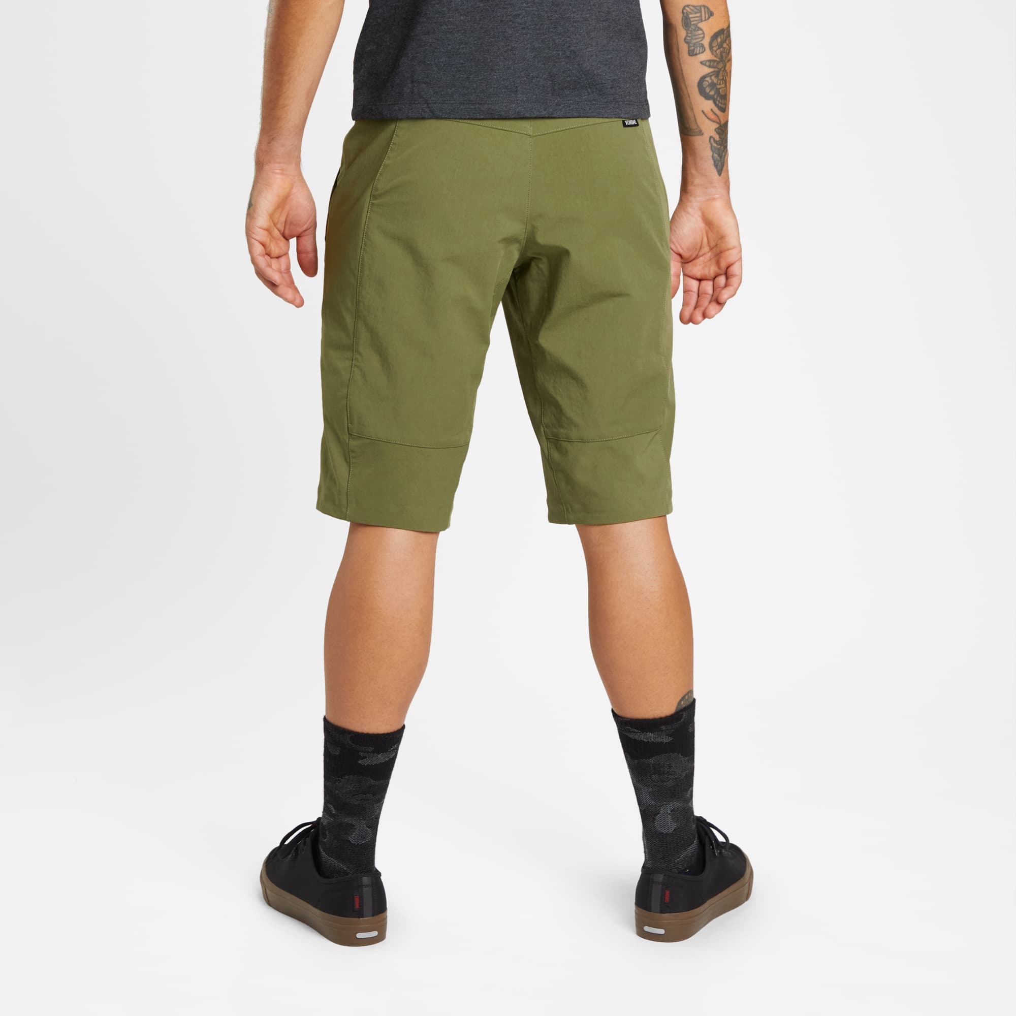 Men's tech Sutro Short in green worn by a man back view #color_olive branch
